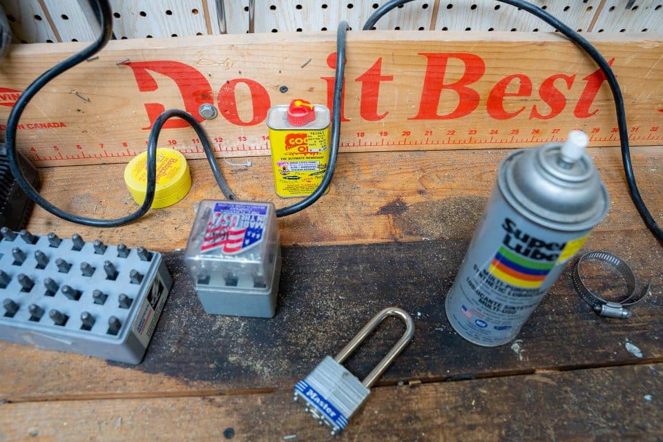 A wooden plank with the Do it Best logo printed in red on it with spray paint and home improvement products in front of it.